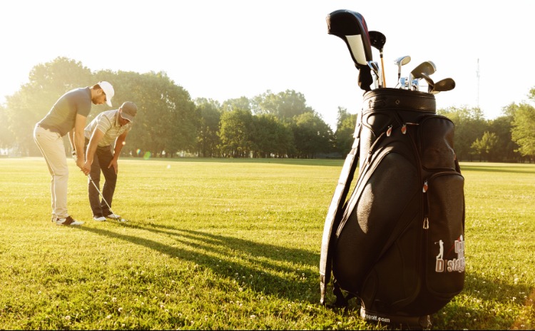 golfers and golf clubs on golf green